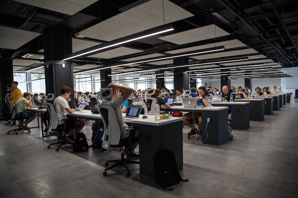 Row after row after row of office workers, sitting at shared desks, working on small laptops.