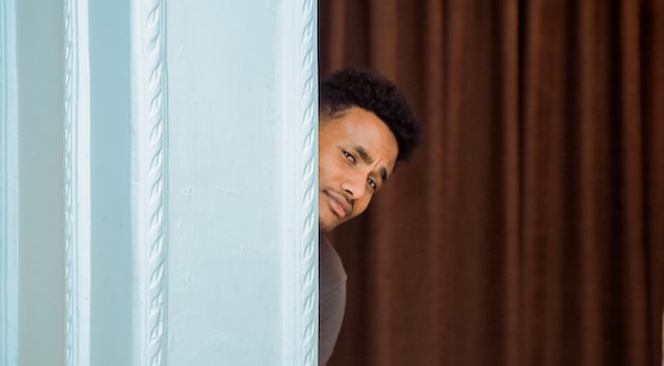 A man peeking his head out from behind a curtain.