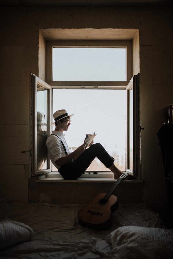 A man sitting in a window and reading.